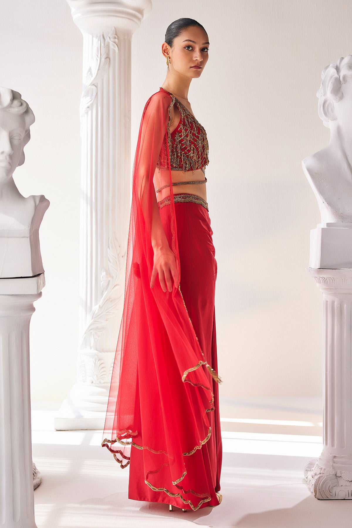 Elegant Red Ensemble Features A Royal Satin Skirt, Fully Embroidered Blouse, Belt And A Cape In A Soft Net.