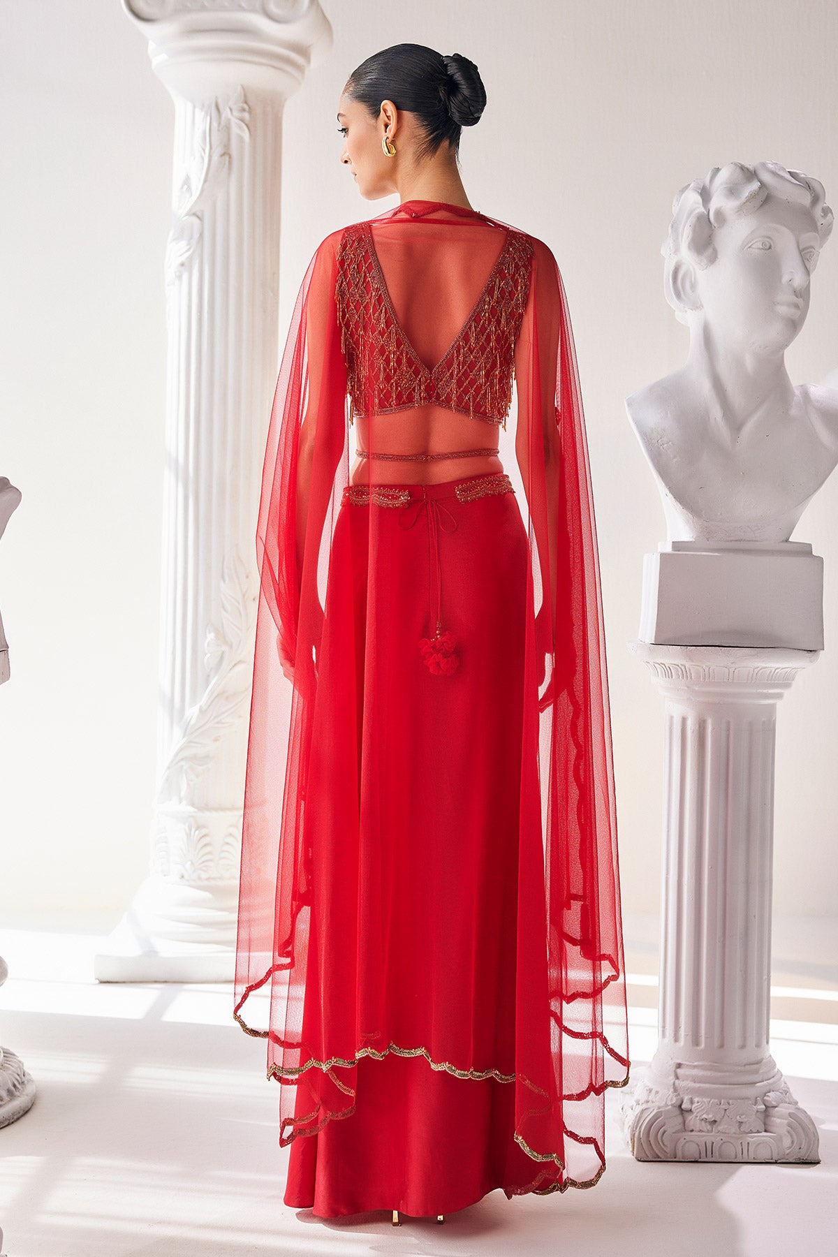 Elegant Red Ensemble Features A Royal Satin Skirt, Fully Embroidered Blouse, Belt And A Cape In A Soft Net.