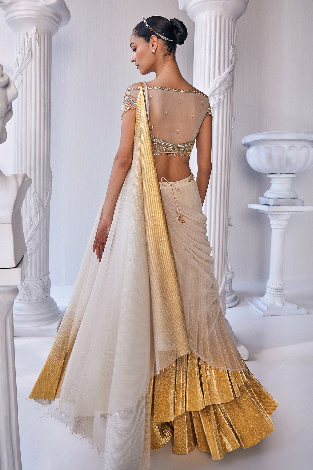 Draped Double Layer Lehenga In Pleated Gold Foil Lycra With An Emroideredwaistband Is Offset With A Corset.