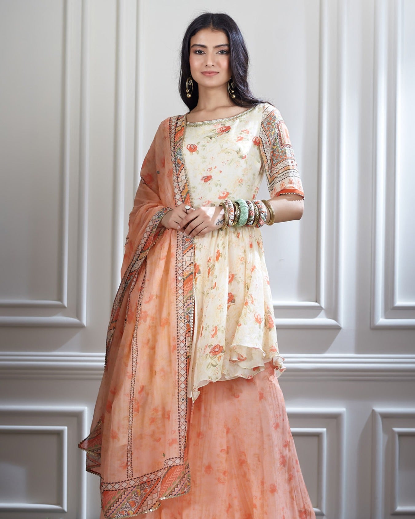 An ivory peplum tunic paired with a printed sharara and dupatta