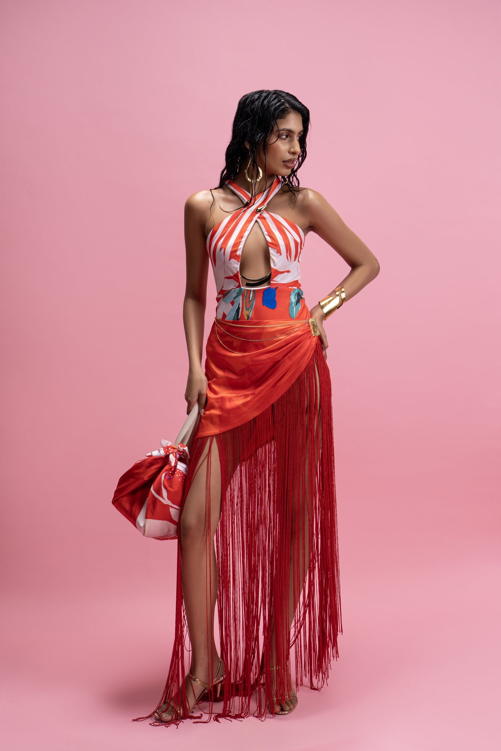 Woman in a red and white dress with a matching handbag against a pink background
