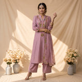 A lavender purple three-piece salwar kameez suit set with floral embroidery, displayed . The set includes a long-sleeve kurta, matching trousers, and a sheer dupatta draped over the shoulder.