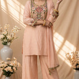 displayed on a mannequin, featuring a long-sleeve embroidered kurta, matching wide-leg pants, and a sheer matching dupatta. The kurta has intricate multicolor embroidery around the neckline and sleeve cuffs, and the pants have matching embroidery at the hem.