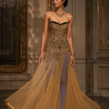 Radiating golden glamour, this strapless evening gown is a stunning play of structure and fluidity.