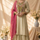 A traditional Indian salwar kameez suit displayed on a mannequin. The outfit features a light sage green kurta with intricate multicolor floral embroidery around the neckline, matching green salwar pants, and a bright magenta dupatta draped over the shoulder.