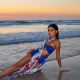 Model wearing a cobalt blue resort wear set with a flowing multicolour printed overlay by Mandira Wirk, photographed on the beach at sunset.