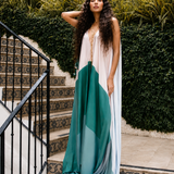 Model wearing a flowing white, teal and aqua colour-block resort kaftan by Mandira Wirk, styled with gold jewellery on patterned outdoor steps.