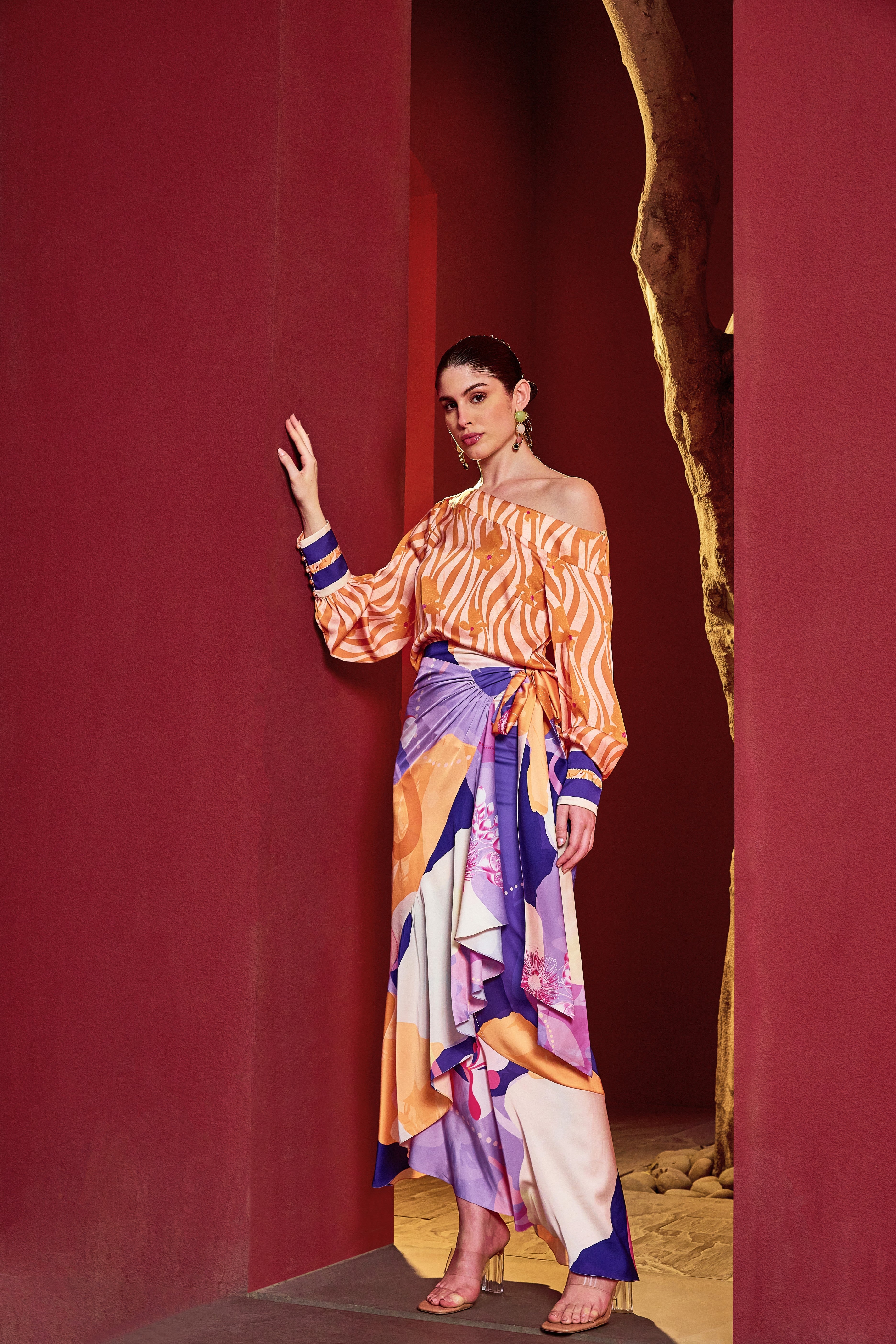 Model wearing Mandira Wirk Orange Eucalyptus co-ord set with off-shoulder printed top and draped trousers.